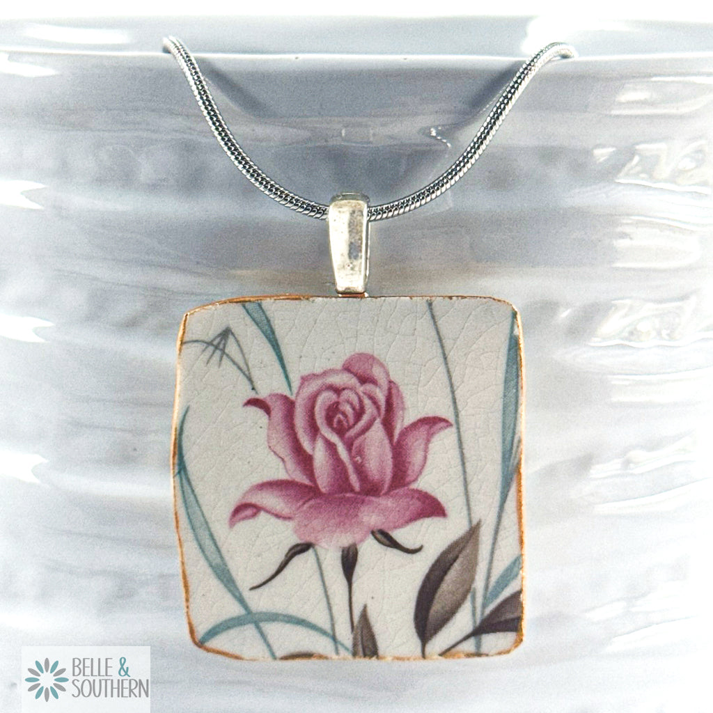 Necklace with a pendant featuring a pink rose design on a white background