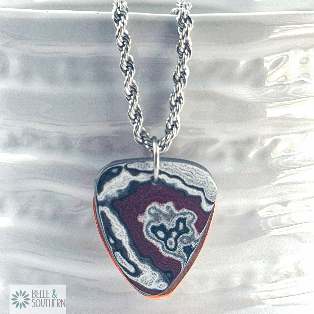 Necklace with multiple color Fordite with copper backing guitar pick pendant, featuring the brand 'Belle & Southern'.
