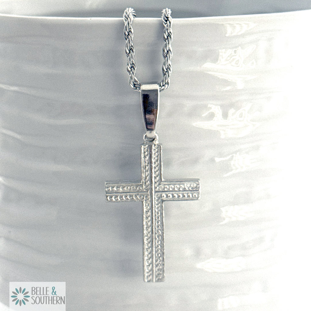 Silver cross necklace on a white marble surface with 'Belle & Southern' branding.