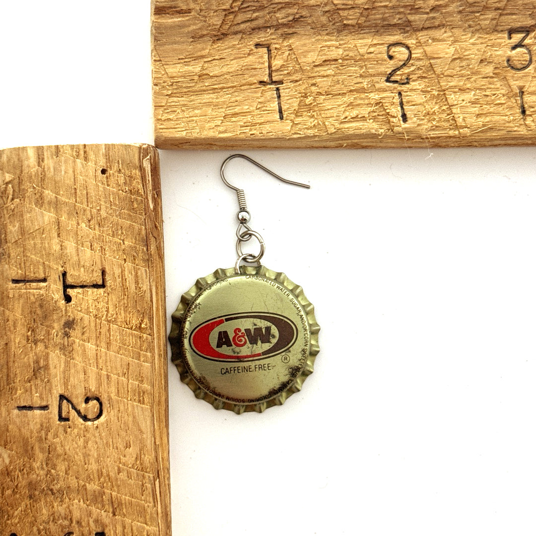 Gold, Orange and Brown Bottle Cap on Stainless Steel Ear Wires Earrings next to ruler