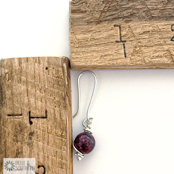 Silver earring with a Aggie Maroon Jade gemstone by a wooden ruler
, with 'Belle & Southern' brand