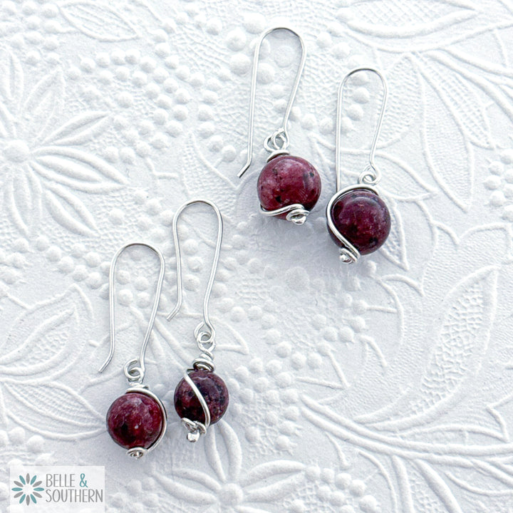 Silver earrings with Aggie Maroon Jade gemstones on a floral textured white background, featuring the brand 'Belle & Southern'.