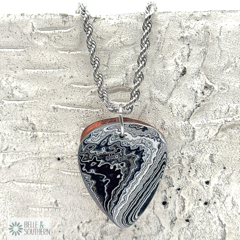 Rope Chain Necklace with a Fordite Guitar PIck shaped pendant on a textured stone surface, featuring the brand 'Belle & Southern'.