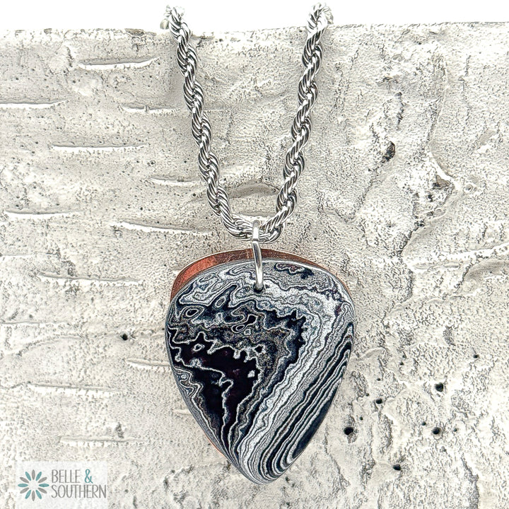 Rope Chain Necklace with a Fordite Guitar PIck shaped pendant on a textured stone surface, featuring the brand 'Belle & Southern'.
