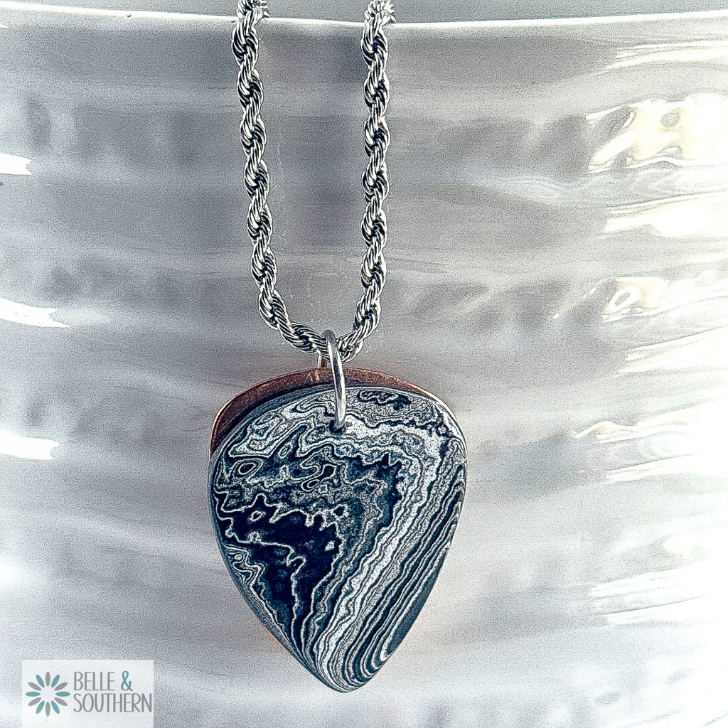 Fordite Guitar Pick with copper backing necklace on white vase featuring belle and southern label