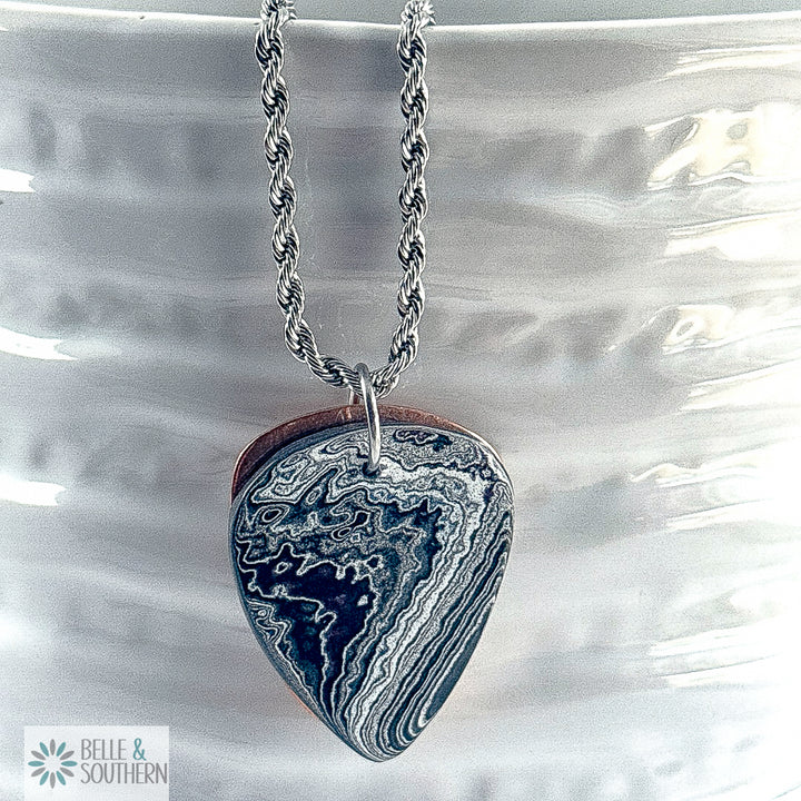 Fordite Guitar Pick with copper backing necklace on white vase featuring belle and southern label