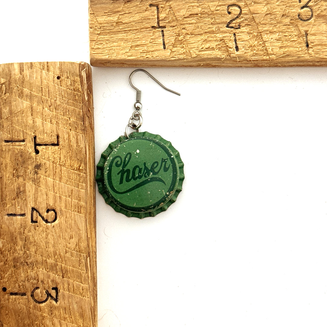 Green Chaser Bottle Cap on Steel Ear Wire Earrings next to ruler