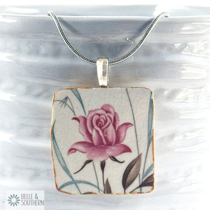 Necklace with a pendant featuring a pink rose design on a white background