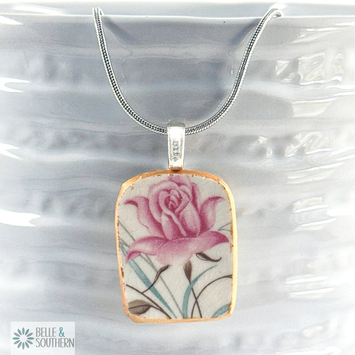Pendant necklace made from vintage floral dinnerware with a blush rose pattern on rhodium chain.
