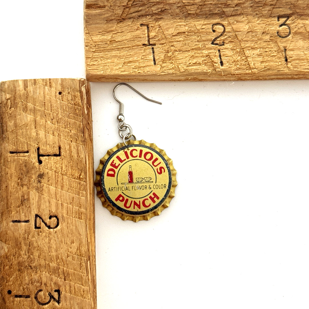 Gold and Red Delicious Punch Bottle Cap on Stainless Steel Ear Wire Earrings next to ruler