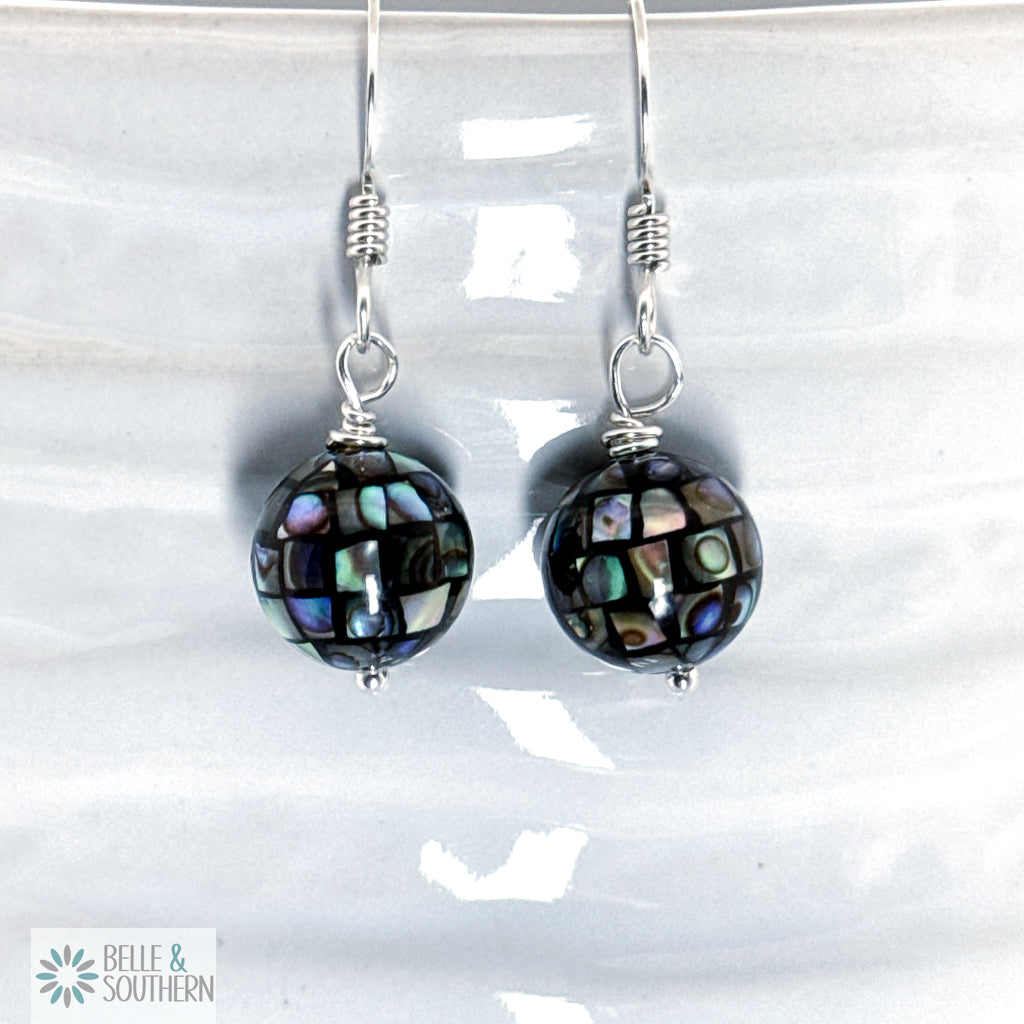 Pair of earrings with irradescent bead on argentium silver ear wires on a white background