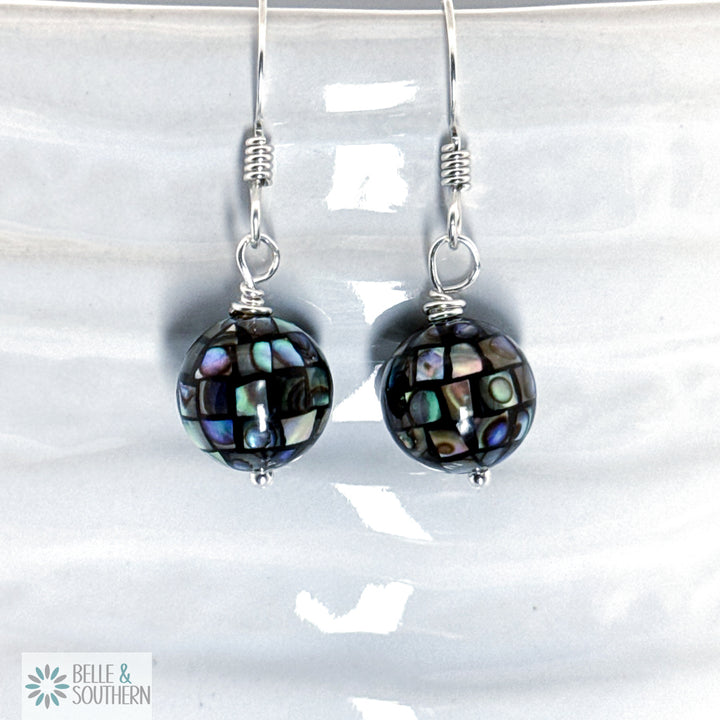 Pair of earrings with irradescent bead on argentium silver ear wires on a white background