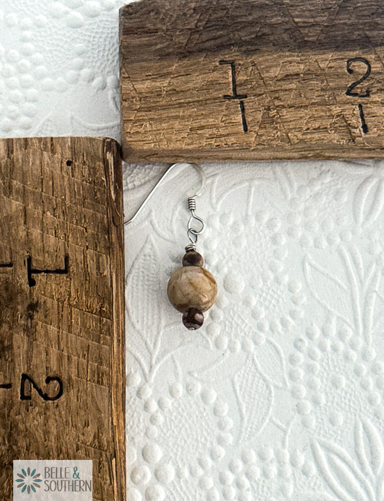 Tan Zebra Jasper stone beaded earring next to a wooden ruler on a textured white surface