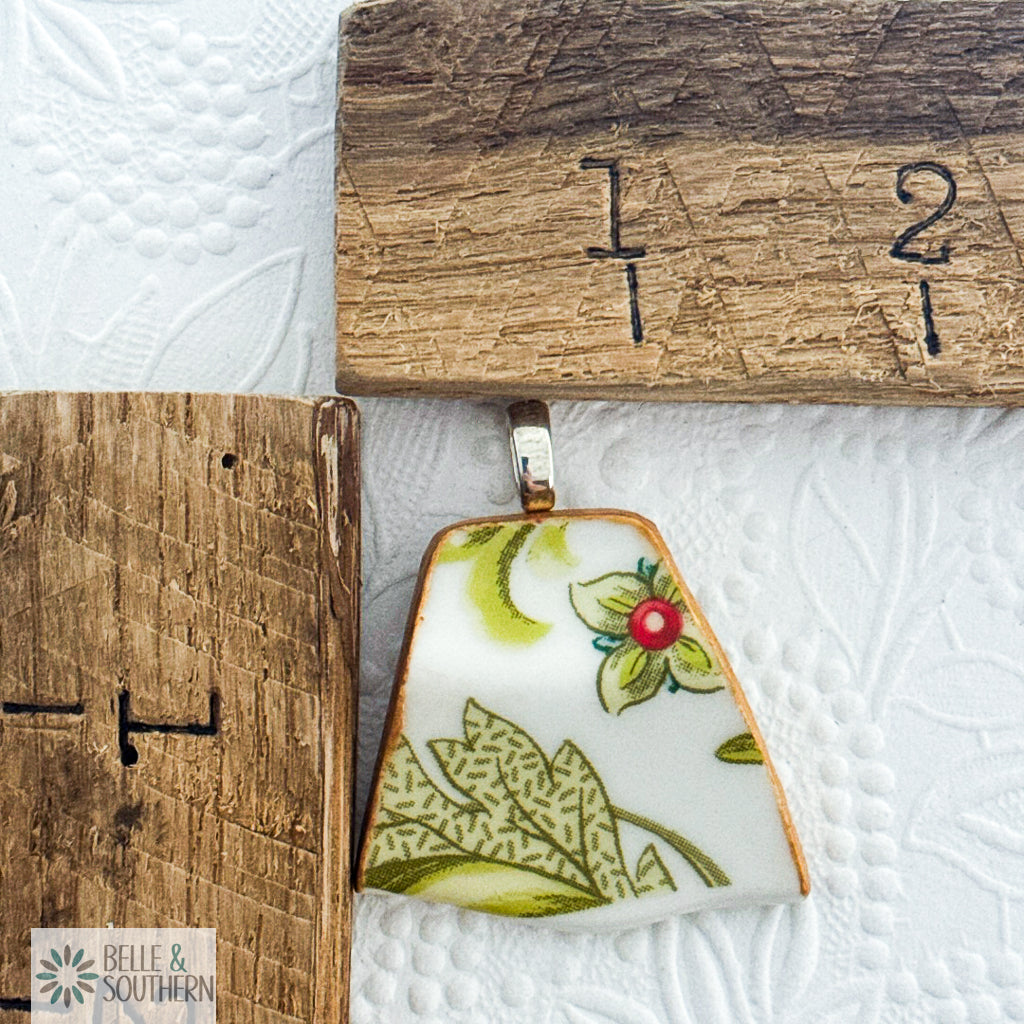 Decorative ceramic pendant with floral design on a white background, next to wooden measurement blocks.