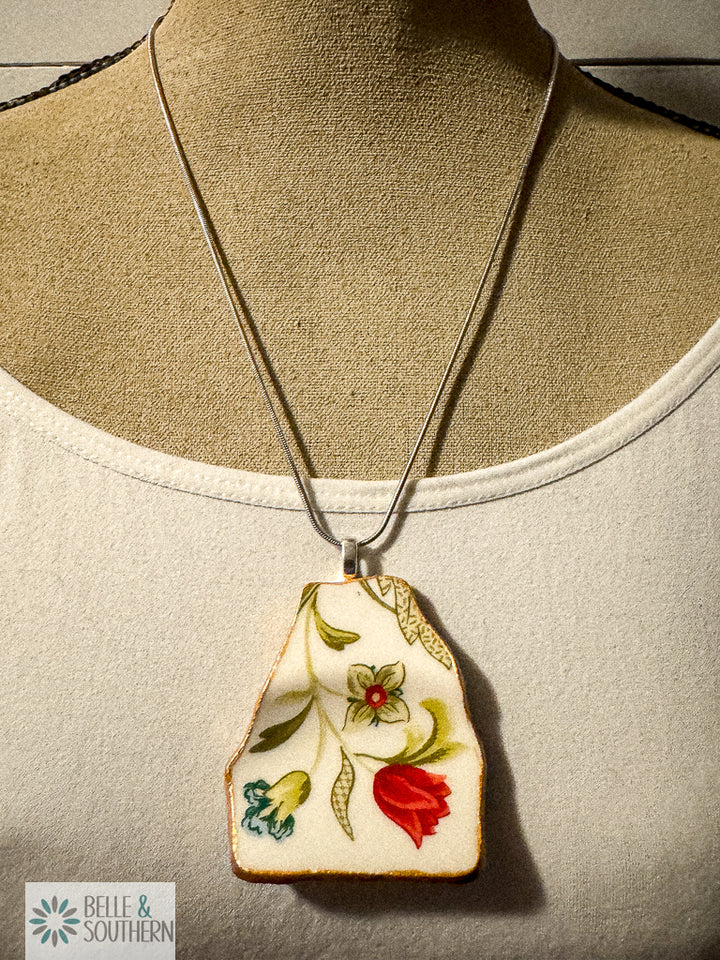 Pendant necklace made from upcycled floral china with red, green, and teal flower pattern and gold edge, on rhodium-plated chain.