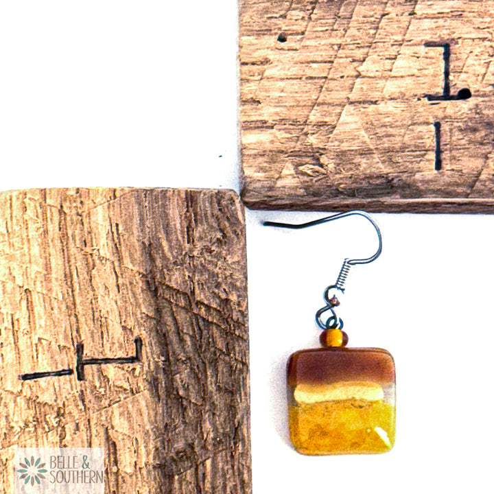 Amber-colored small square glass earring by wooden rulers with 'Belle & Southern' branding.
