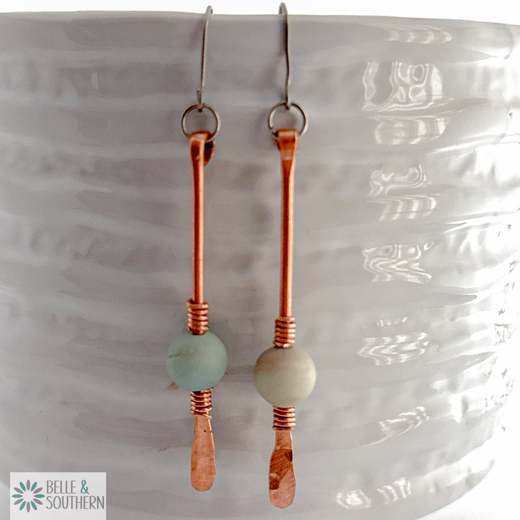 Amazonite Gemstone on copper wire dangle earrings resting on a white vase