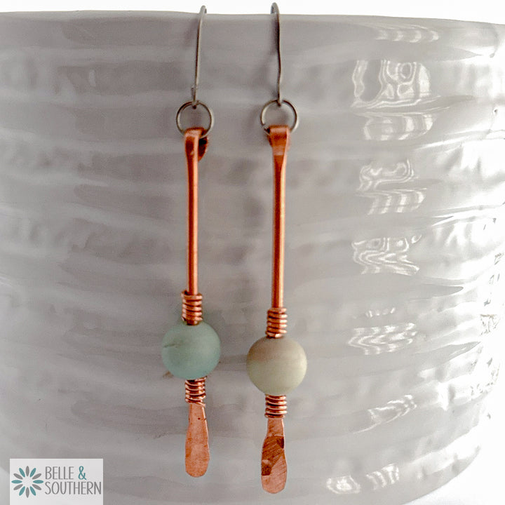 Amazonite Gemstone on copper wire dangle earrings resting on a white vase