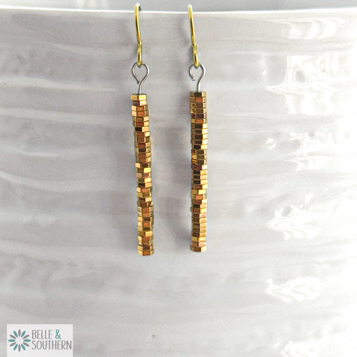 Pair of gold stacked hematite earrings on a white vase featuring 'Belle and Southern' brand

