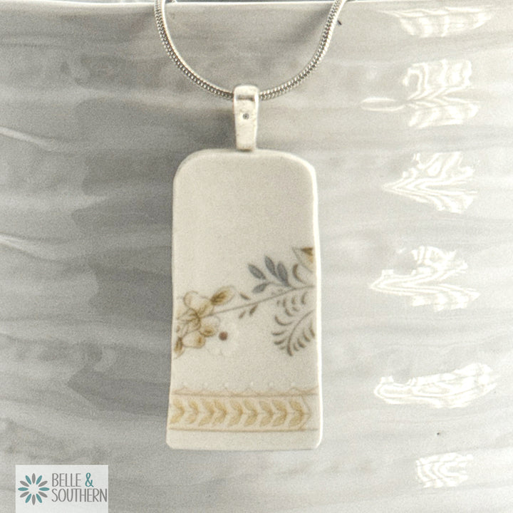 Rectangular pendant with floral design necklace on a white vase, featuring the brand 'Belle & Southern'.