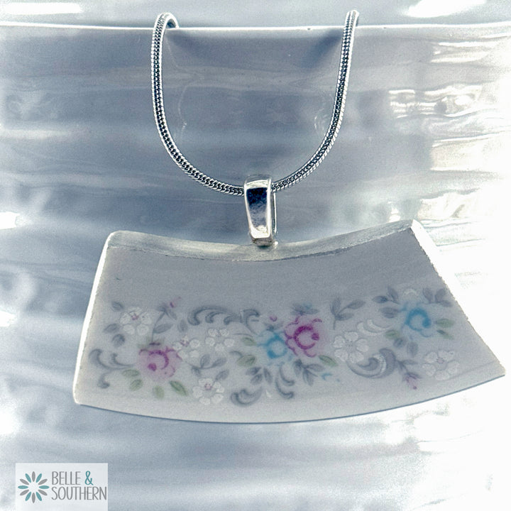 Semi-circular pendant with floral design on a clear stand against a white background, branded 'Belle & Southern'.