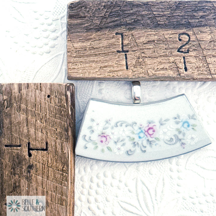 floral-patterned dinnerware next to wooden rulers on a textured white surface.