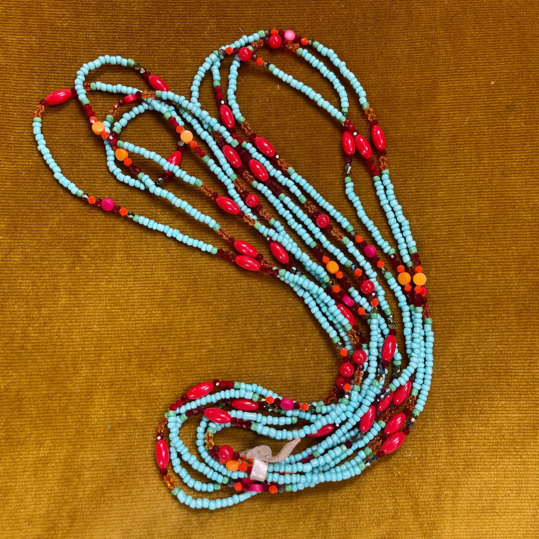 Set of three colorful glass bead necklaces displayed coiled on tan background
