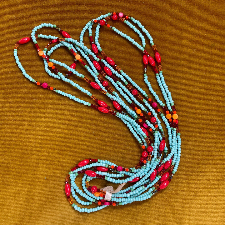 Set of three colorful glass bead necklaces displayed coiled on tan background
