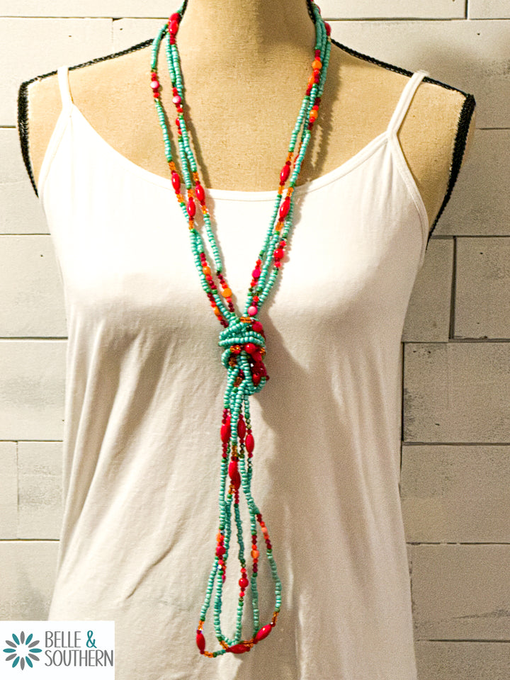 Three handmade glass bead necklaces styled long and layered on mannequin torso