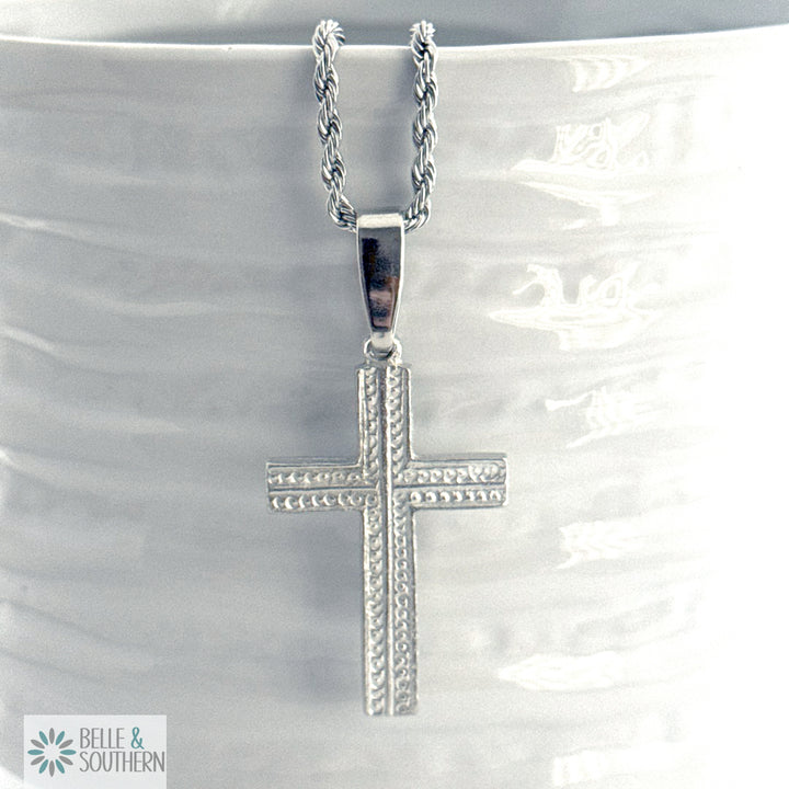 Silver cross necklace on a white marble surface with 'Belle & Southern' branding.