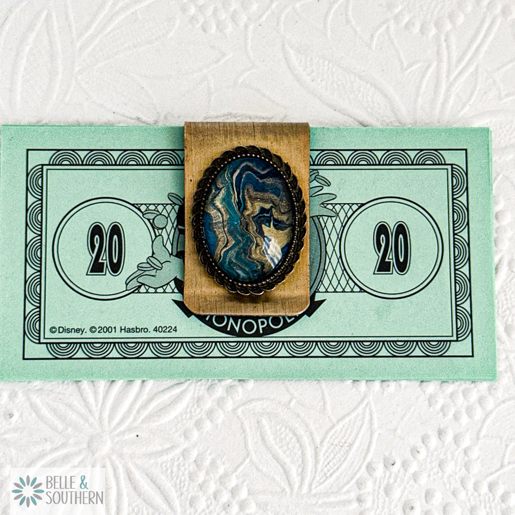 Gold Money Clip with Teal and Gold Paint Skin in glass holding 'Monopoly' branding.