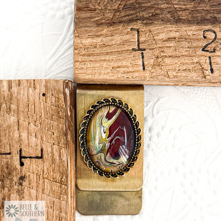 Gold Stainless Steel Money Clip with Burgundy, Gold and Olive Green marbled stone looking paint with decorative border by ruler, branded 'Belle & Southern'.