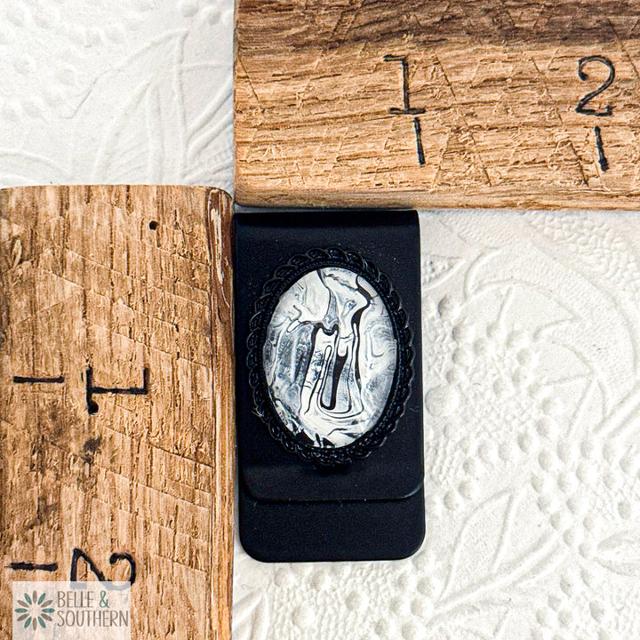 Black Stainless Steel Money Clip with Silver, Black and white marbled stone looking paint with decorative border by ruler, branded 'Belle & Southern'.