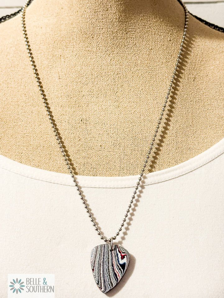 Redline Swirl Fordite guitar pick necklace with stainless steel bead chain on a manequin