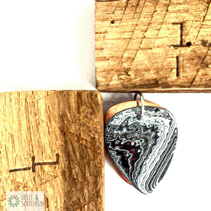 Fordite Pendant in a Guitar Pick Shape next to a ruler