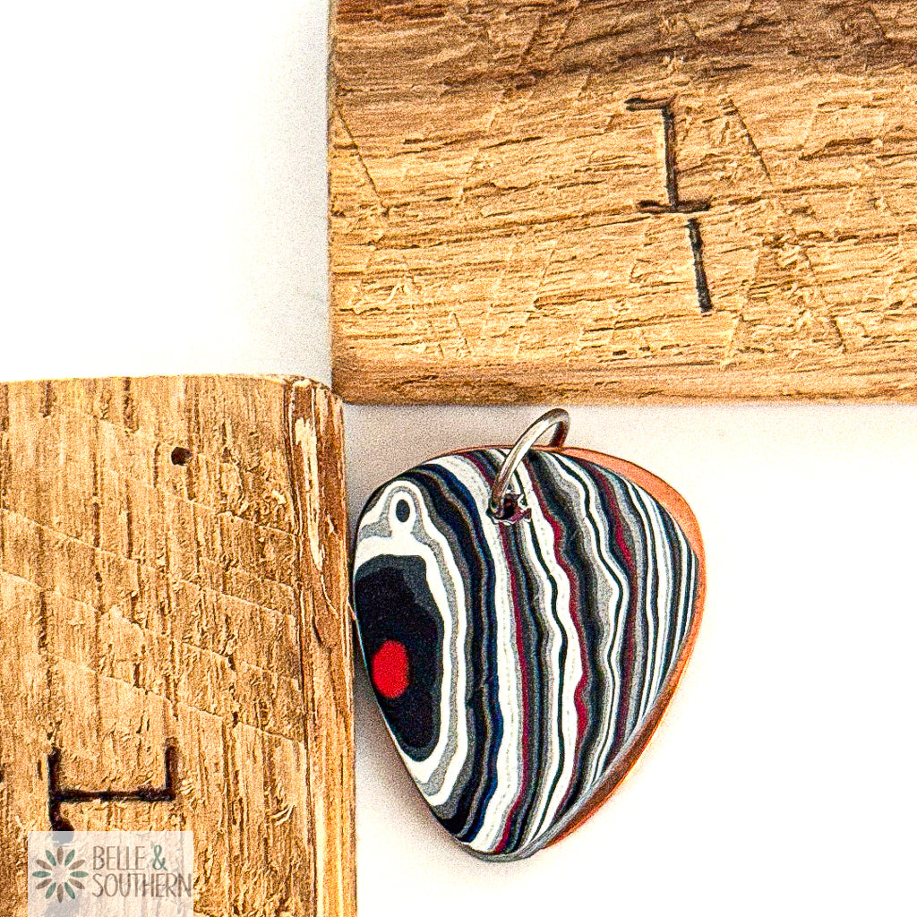 Fordite Guitar Shape Pendant next to ruler