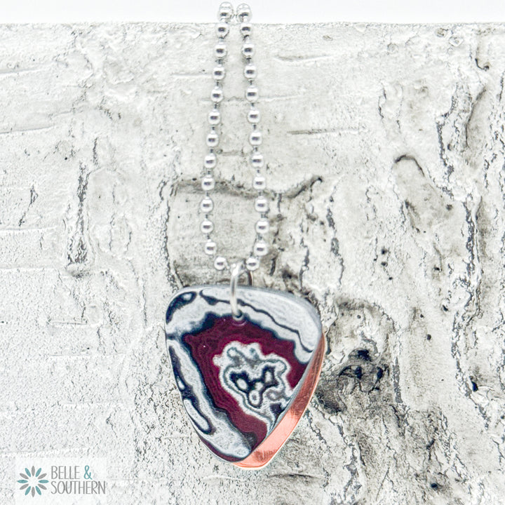 Fordite Guitar Pick Shaped Necklace on a Bead Chain on a stone backdrop