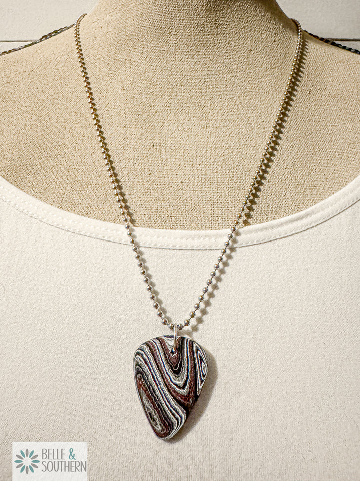 Factory Flame Fordite necklace with marbled red and white pattern in guitar pick shape