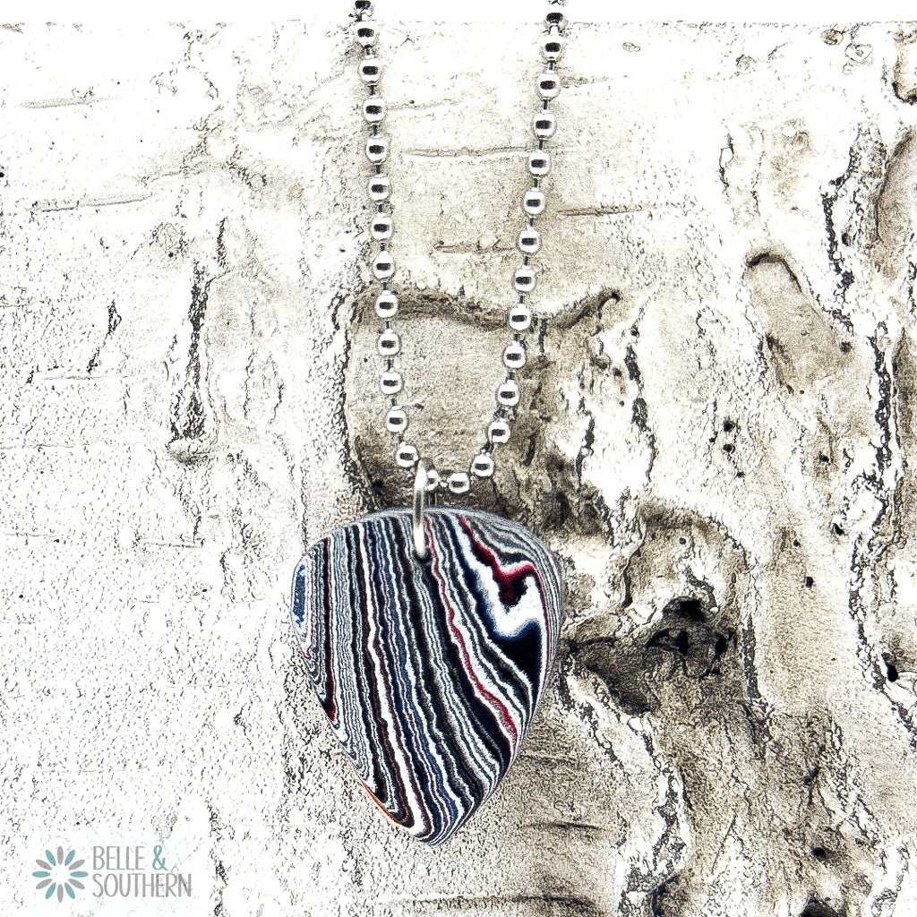 Necklace with a striped pendant on a bead chain on textured white background