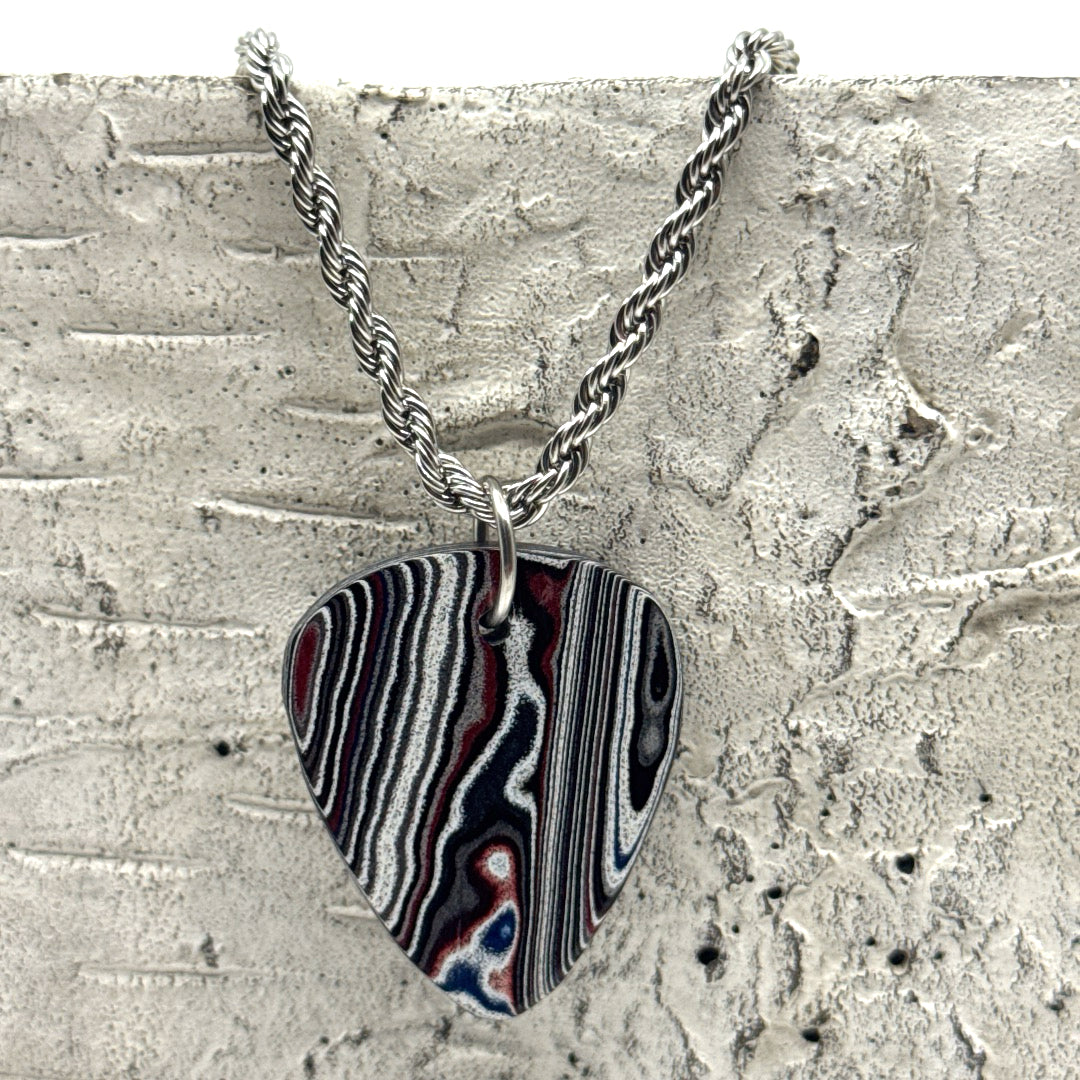 Necklace with a guitar pick-shaped pendant hangin on a textured surface