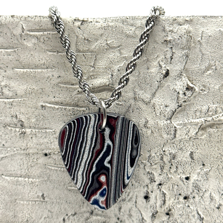 Necklace with a guitar pick-shaped pendant hangin on a textured surface