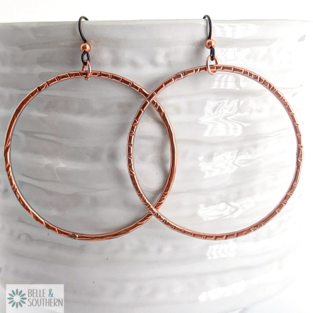 Copper hoop earrings on a white vase with 'Belle & Southern' branding.