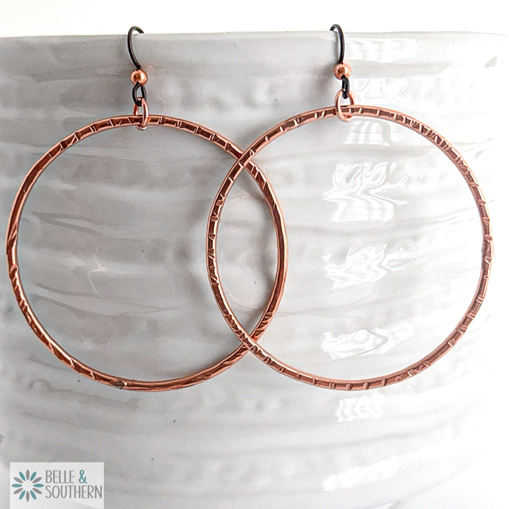 Copper hoop earrings on a white vase with 'Belle & Southern' branding.
