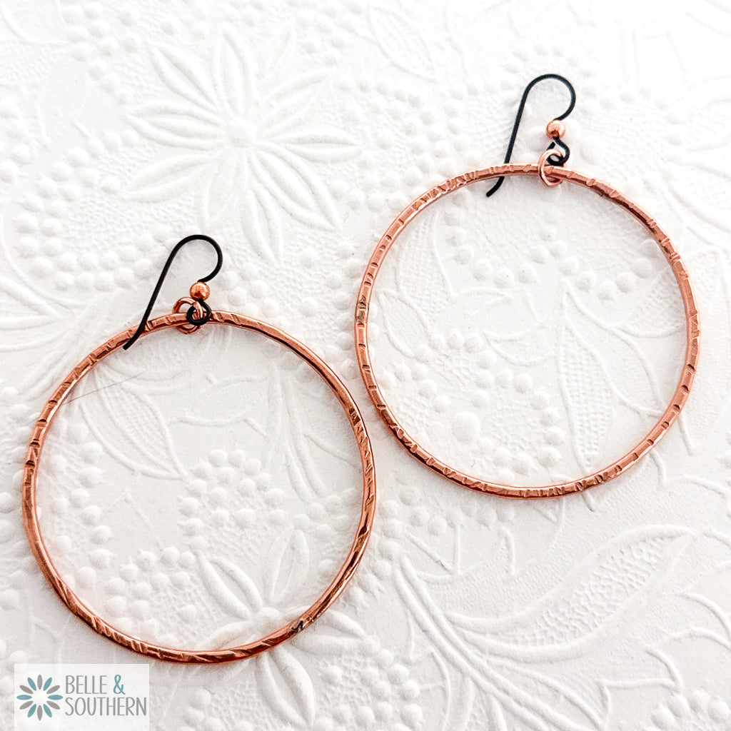 Copper hoop earrings on a floral textured white background with 'Belle & Southern' branding.
