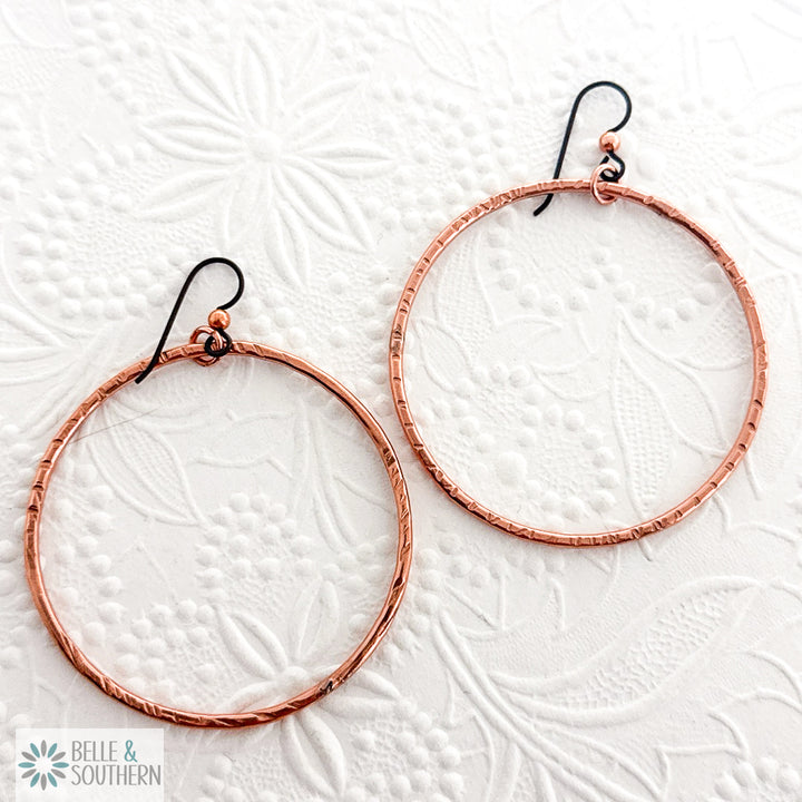 Copper hoop earrings on a floral textured white background with 'Belle & Southern' branding.