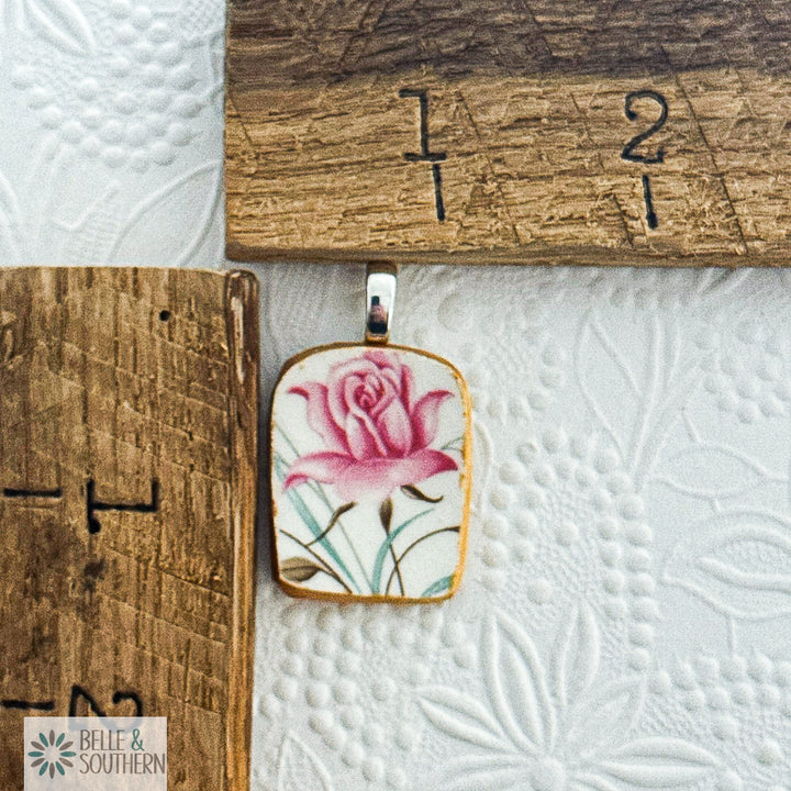 Pendant with floral design on a wooden ruler and textured white surface to provide measurent