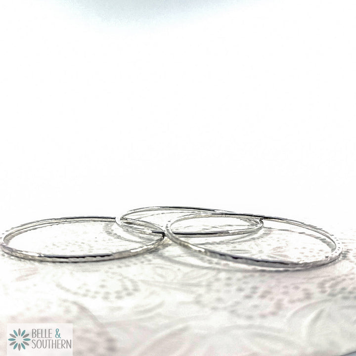 Handforged sterling silver bangles on floral backdrop, artisan made in Ball Ground GA