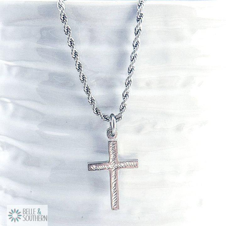 Silver cross necklace on a textured white background with 'Belle & Southern' branding.