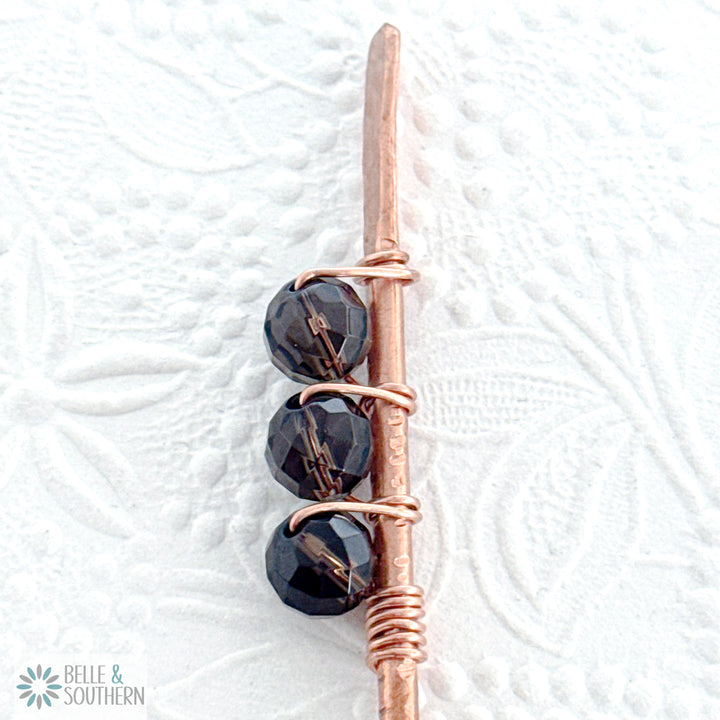 Close-up of faceted smoky quartz gemstone beads wrapped on a textured copper hair stick shown for reference 