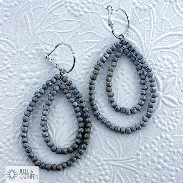 Pair of silver/gray beaded teardrop earrings on a textured white background with 'Belle & Southern' branding.